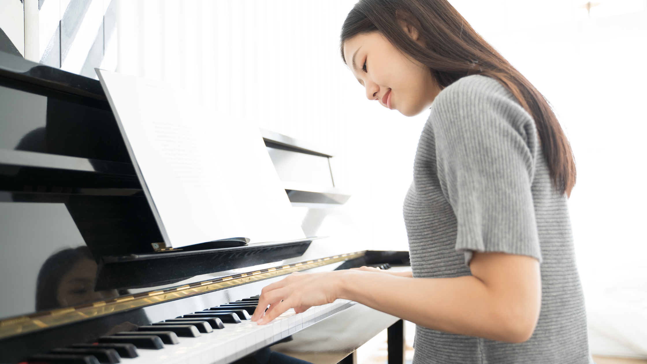 年輕女子在明亮的房間裡彈鋼琴和閱讀樂譜。