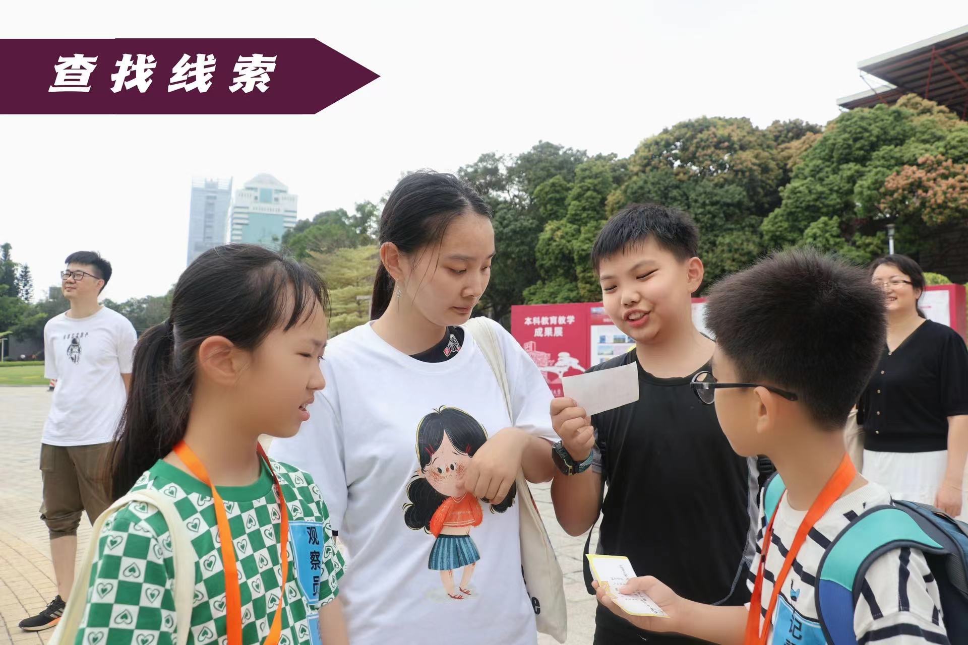 一群孩子和一名年輕女子聚集在戶外。一個孩子指著她手上的東西，另一個孩子拿著一張紙。圖像中的文字為中文。