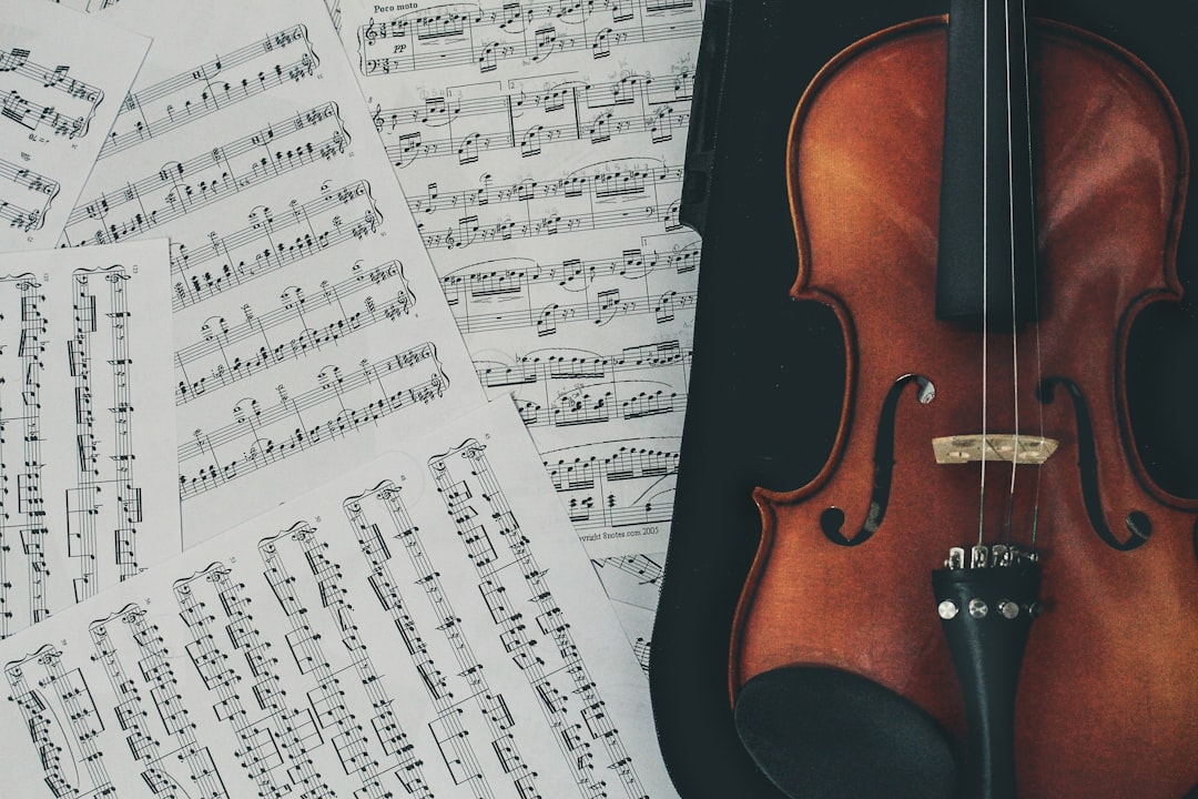 一把小提琴放在散落的古典音樂印刷紙張旁邊。. Photo violin teacher qualification